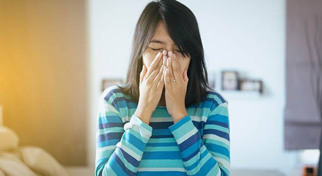 woman sneezing due to allergies in College Station, Texas
